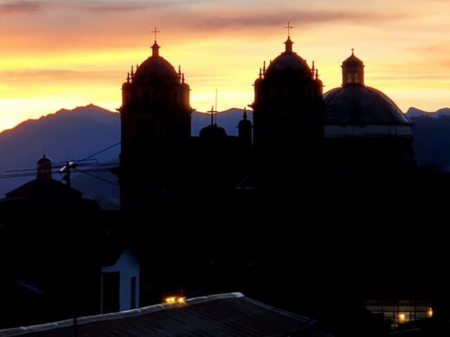 Colorful sunrise over rooftops and churches in Cusco