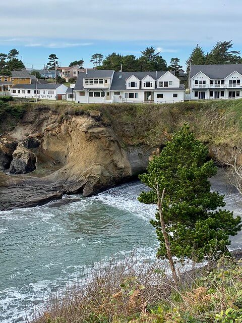 Inn at Arch Rock three white buildings. perched above Depoe Bay Pacific Ocean on Oregon Coast. West Building one-story, Center and East Building both 2-story. 