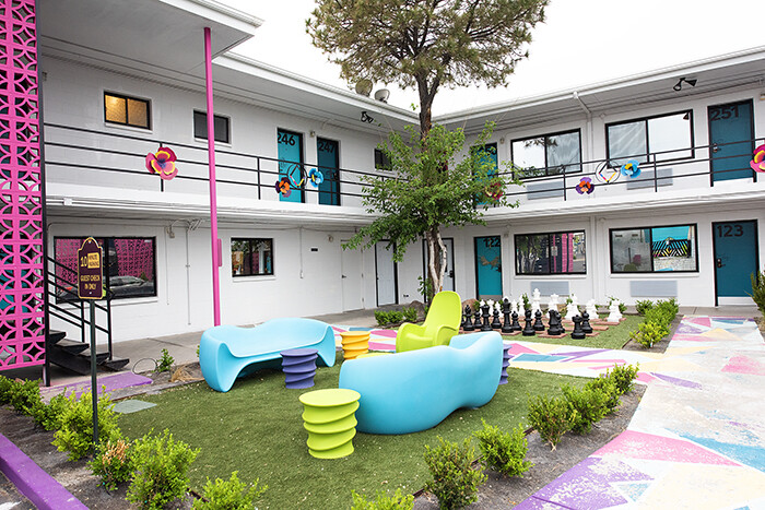 Brightly colored plastic furniture and a large lawn chess set sit in the courtyard of the two-story hotel