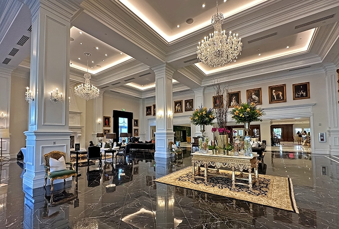 The grand lobby features a black marble floor, crystal chandeliers, and gold-gilded furniture