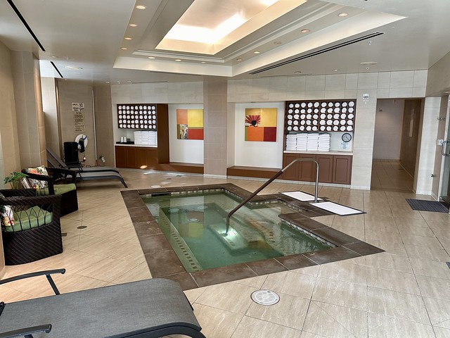 Ladies' locker room hot tub with chocolate brown woven fabric chaise lounges and white spa towels.