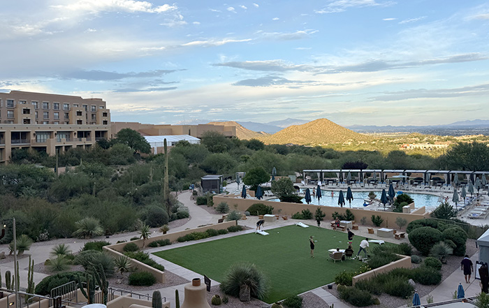 A green lawn with cornhole and a luxe swimming pool look out over the desert from the rear courtyard of Tucson Desert Starr Pass