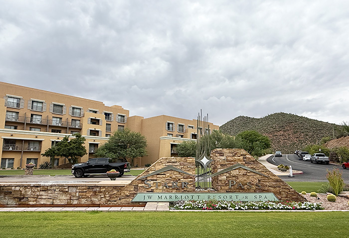 A stone wall with signage saying JW Marriott Starr Pass Resort & Spa welcomes guests