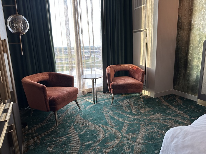 Twor chairs and a table in front of the large window.