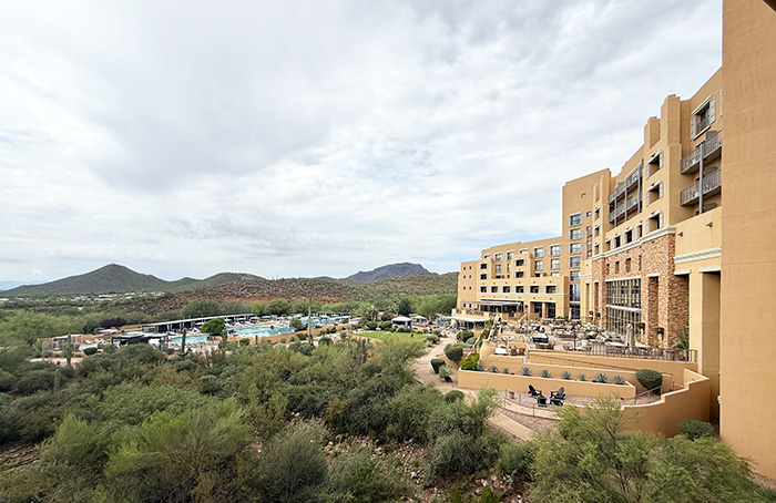 The rear view of Tucson Desert Starr Pass shows the hotel wrapping around a back yard complete with a large patio, green lawn, and expansive pool area.