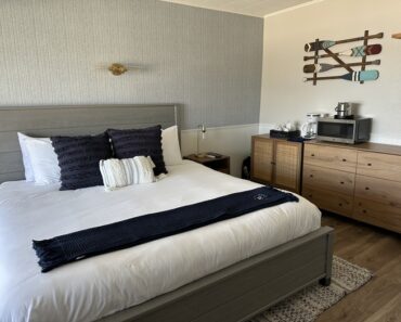 A bed in a hotel room beside a dresser.