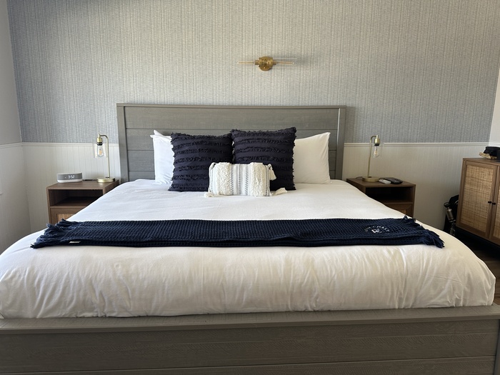 A king size bed with blue pillows at the Fresh Coast Motel.