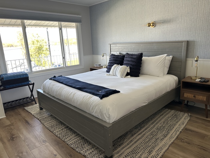 A view of the room with a bed, the windows and luggage rack in the Fresh Coast Motel. 